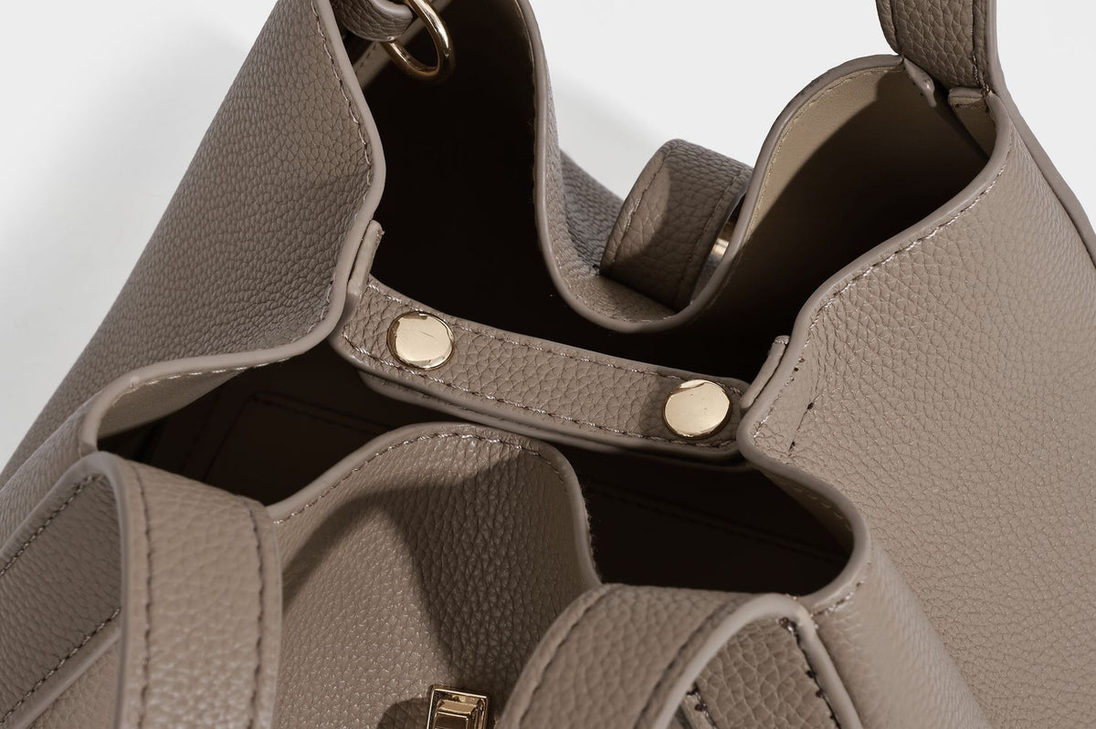 Structured trapezoid tote bag in taupe pebbled leather-look finish with gold-tone turn-lock hardware, dual top handles, and