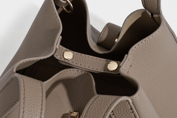 Structured trapezoid tote bag in taupe pebbled leather-look finish with gold-tone turn-lock hardware, dual top handles, and