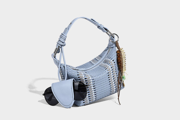 Small woven crescent shoulder bag with leather-look trim, zip closure, silver-tone ring hardware, and beaded tassel charm