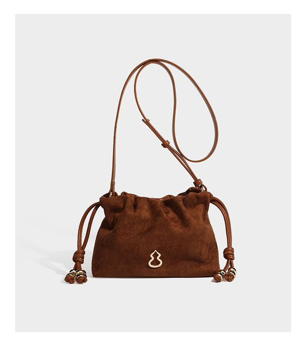 Suede-look drawstring shoulder bag in brown with smooth trim, knotted bead drawstring closure, slim adjustable strap, and