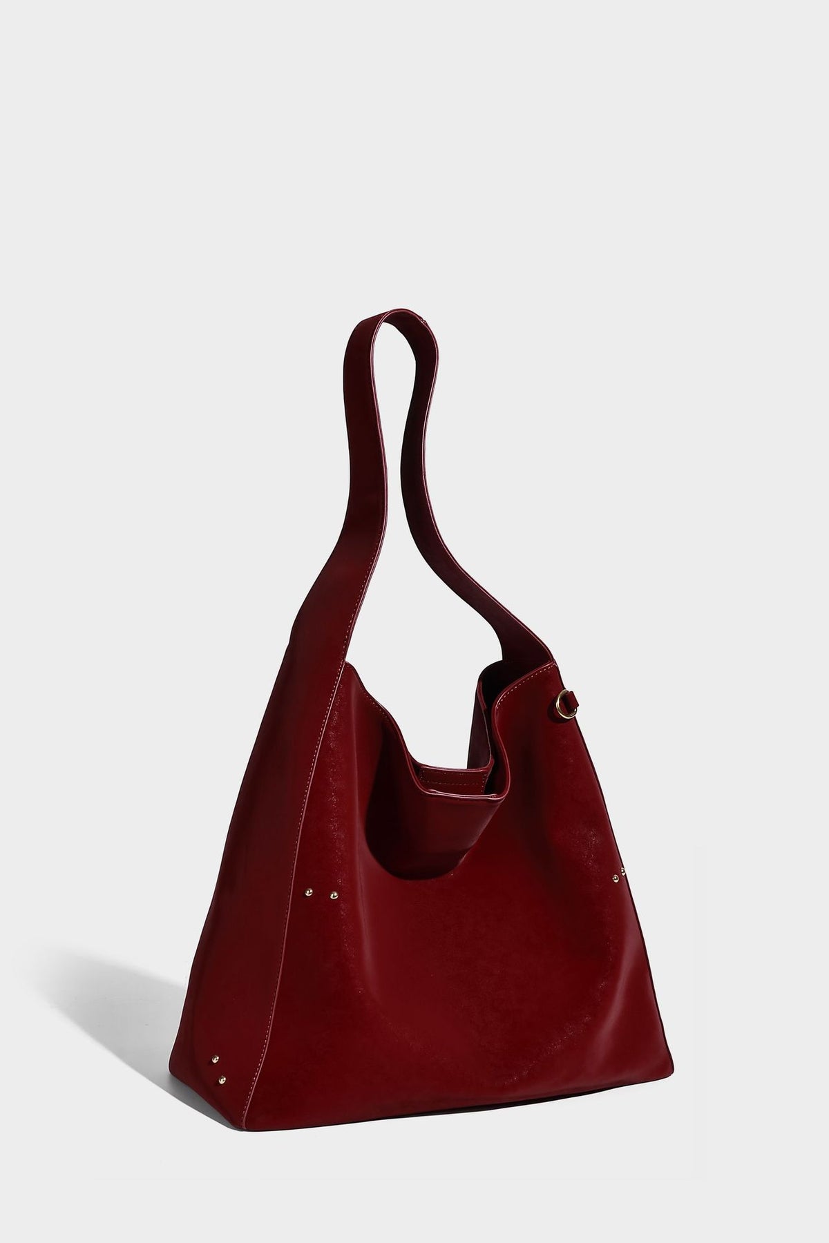 Oversized trapezoid tote bag with matte leather-look finish, gold-tone rivets, and long shoulder strap, detail view 16