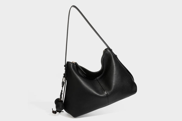 Slouchy hobo shoulder bag with pebbled leather-look finish, zip-top closure, gold-tone hardware, and hanging bead charm
