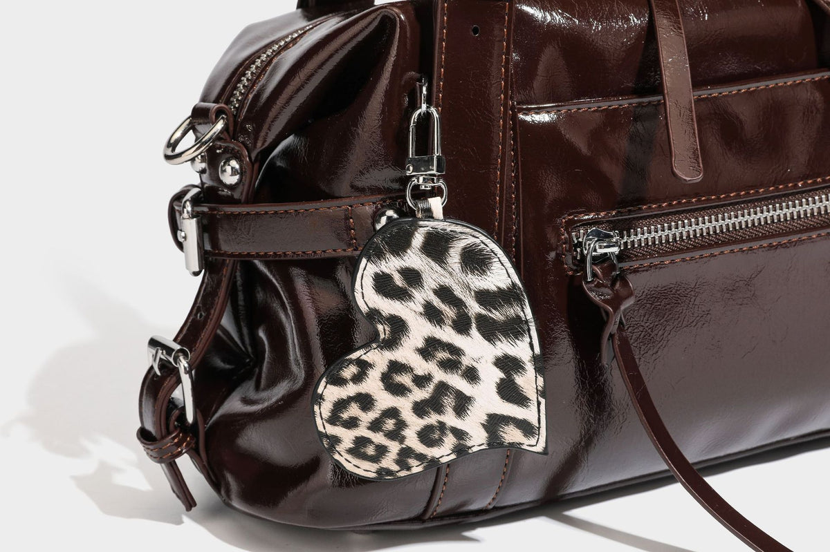 Strukturierte Schultertasche in glänzender Lederoptik mit abgerundetem Korpus, silberfarbenen Beschlägen, Reißverschlussfach auf der Vorderseite und Leopardenmuster