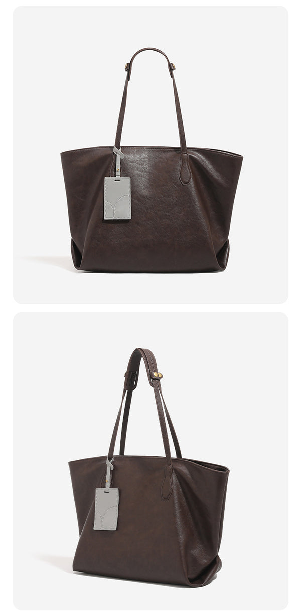 Oversized slouchy leather-look tote bag with long shoulder straps, contrast grey hanging tag, and silver-tone hardware