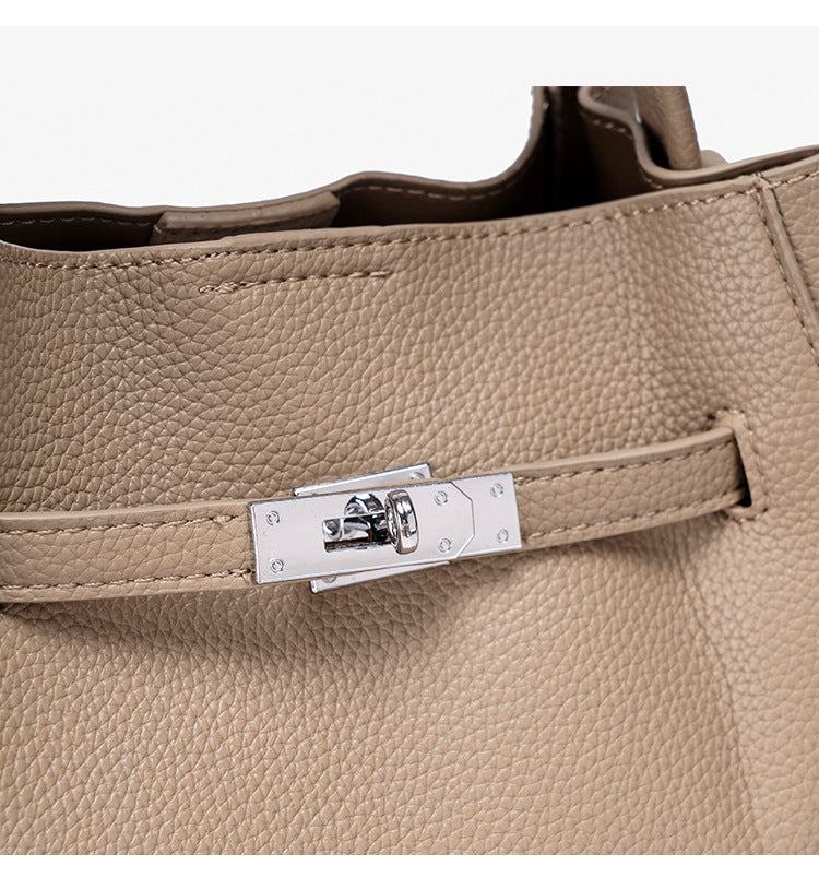 Compact structured bucket bag in pebbled leather-look finish with silver turn-lock front clasp, dual top handles, detachable
