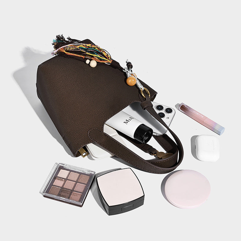 Kleine Beuteltasche mit genarbter, matter Oberfläche, antikgoldfarbenen Ringbeschlägen, Perlen- und Quastenanhänger, kurzen Henkeln und