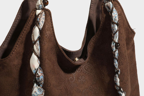 Slouchy paisley-embossed suede-look shoulder tote bag with braided patterned fabric straps and wood bead accents, detail view