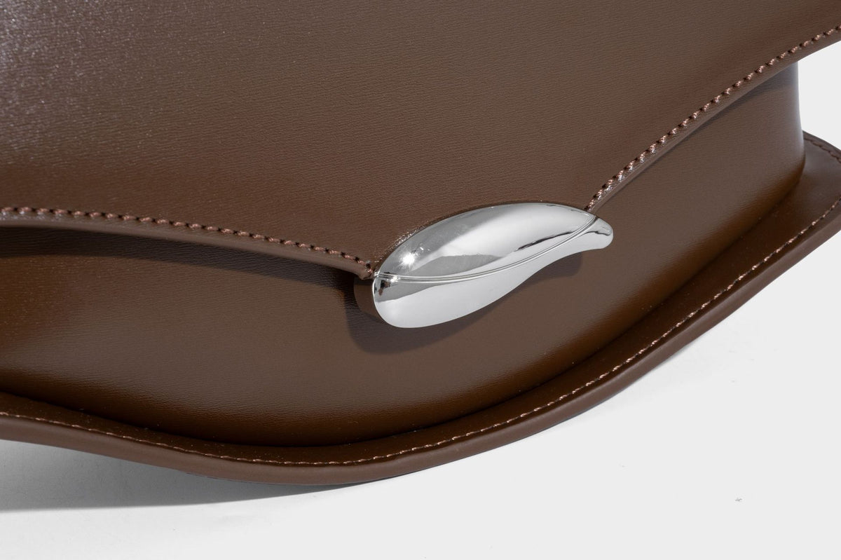 Small structured saddle bag with glossy leather-look finish, angular flap front, silver-tone metal clasp, and slim
