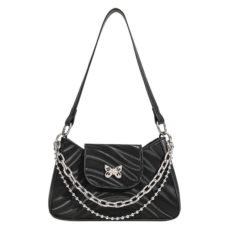 Small trapezoid shoulder bag with ripple leather-look finish, silver butterfly front clasp, and layered chain-and-ball strap
