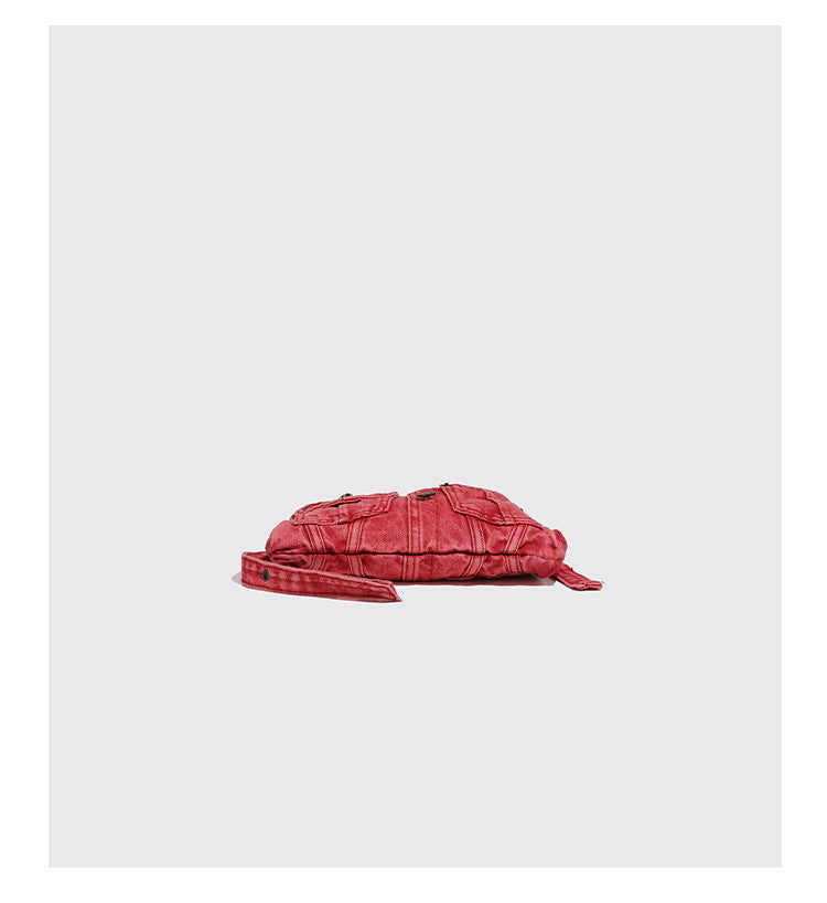 Compact washed red distressed-textile shoulder bag with front flap pockets, dark metal hardware, and long adjustable strap