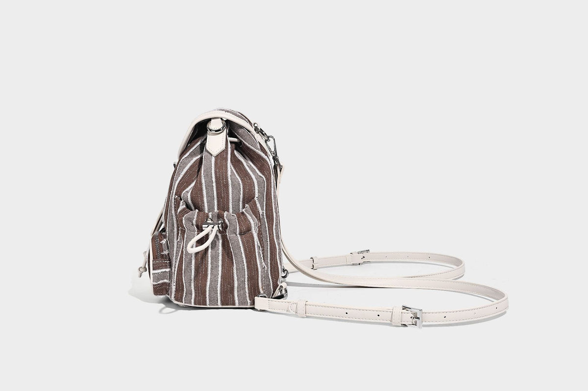 Weicher Rucksack aus gewebtem Material mit vertikalen Streifen, Überschlag, Kordelzug, vorderer Reißverschlusstasche, weißen Besätzen und Trägern in Lederoptik, Detailansicht