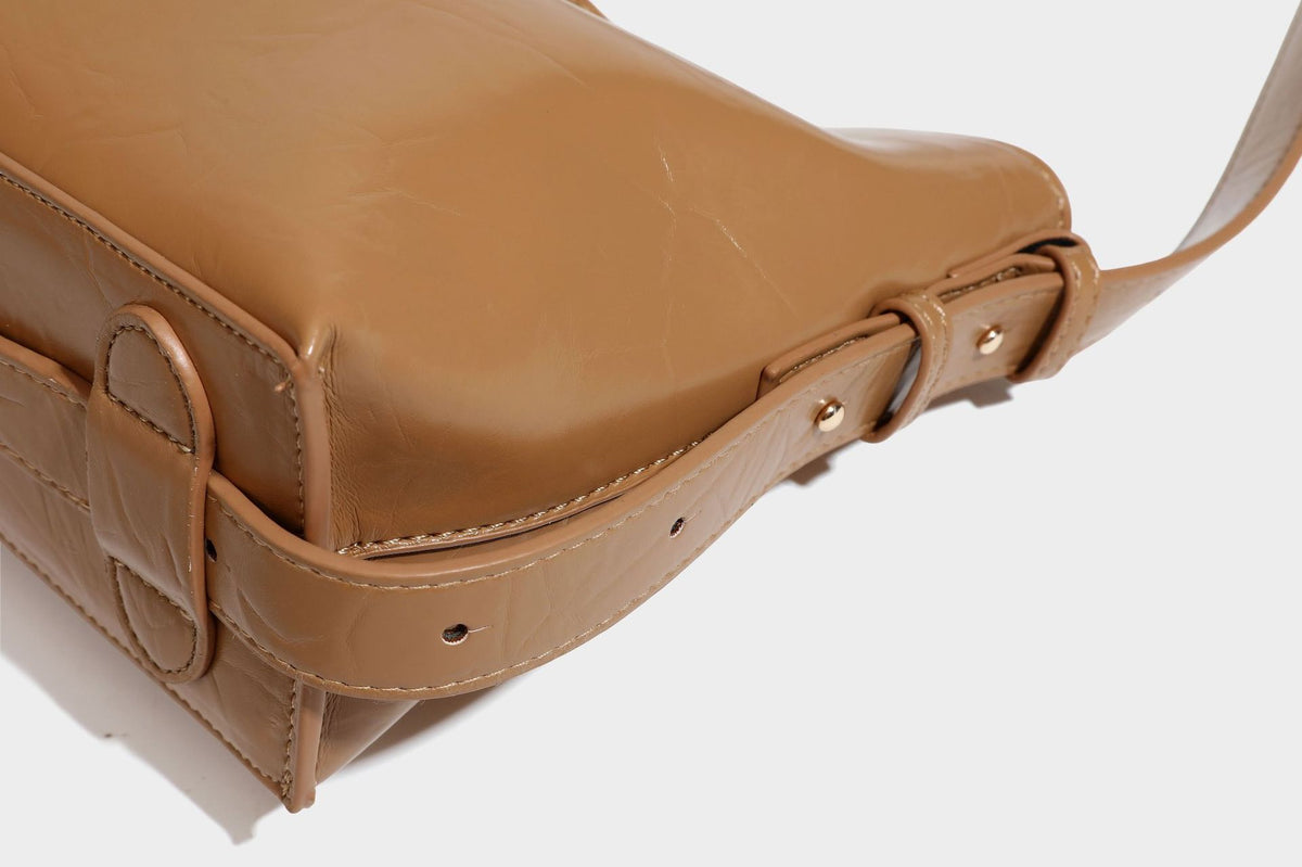 Lässig fallende Hobo-Schultertasche mit offenem Oberteil aus glänzender, karamellbrauner Lederoptik, mit Logo-Beschlägen in Goldoptik und langem, verstellbarem