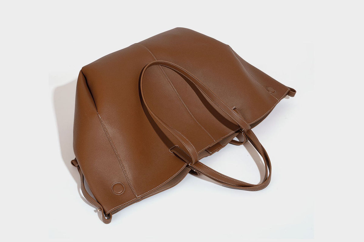 Große, formstabile trapezförmige Tote-Bag aus braunem Lederimitat mit genarbter Oberfläche, zwei Tragegriffen und seitlichen Bindebändern, Detail