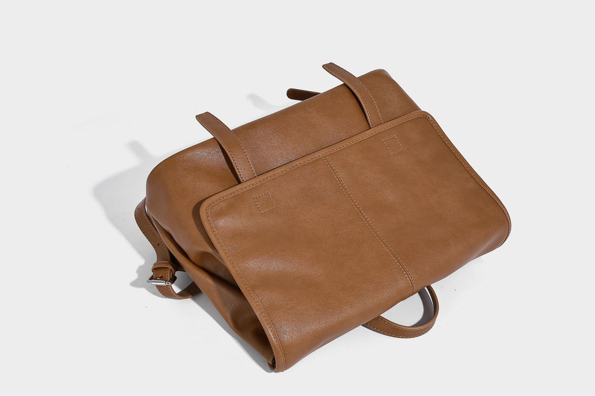 Structured tan leather-look flap backpack handbag with top handle, silver buckle hardware, and fold-over front closure