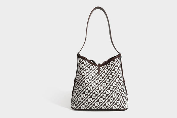 Woven geometric bucket shoulder bag in white and dark brown two-tone pattern with leather-look trim and drawstring top