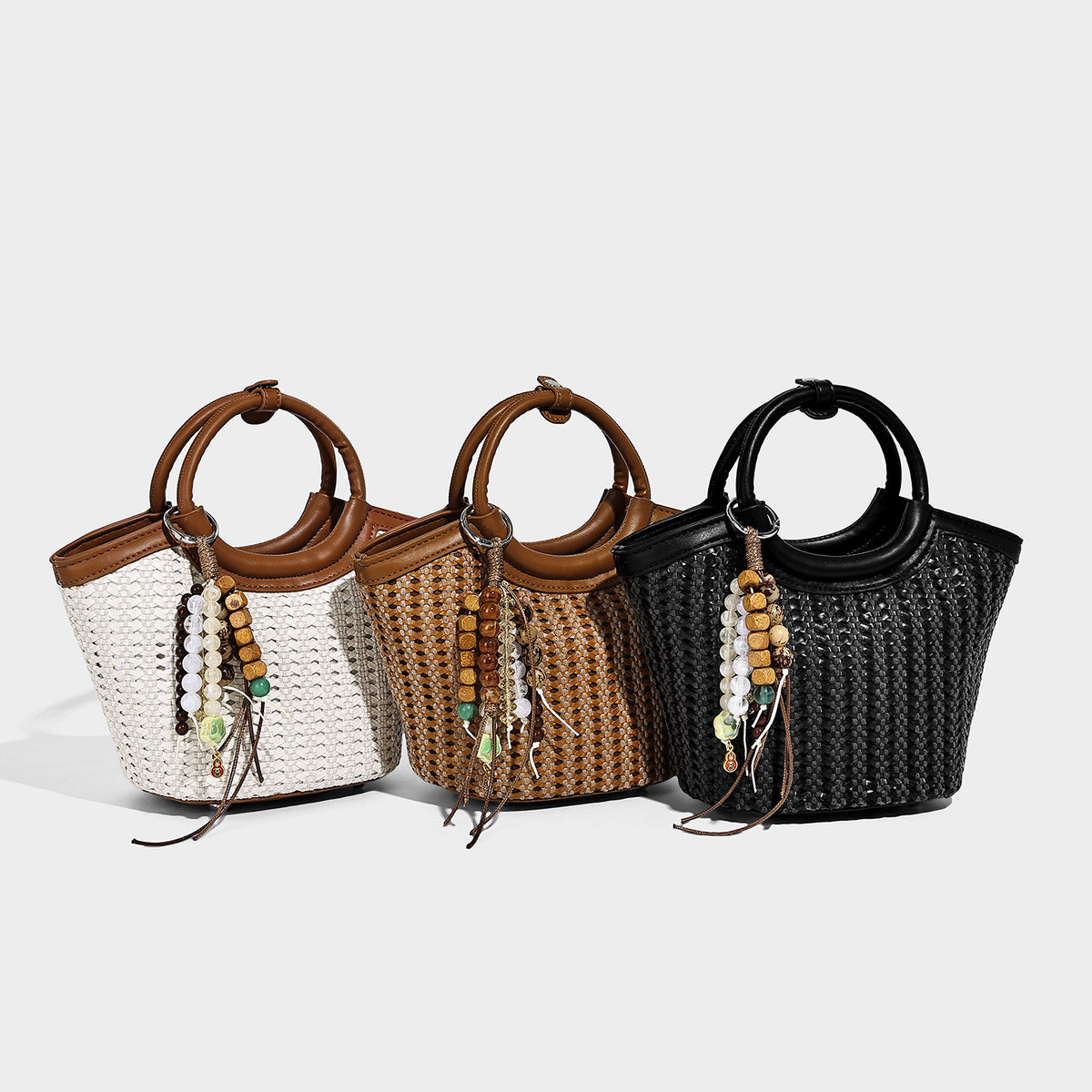 Small woven bucket bag with round leather-look ring handle, beaded tassel charm, and detachable crossbody strap in tan brown