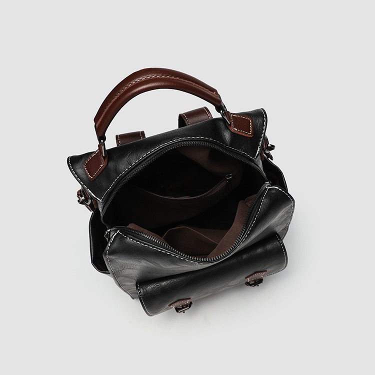 Structured black leather-look convertible backpack handbag with brown contrast trim, buckle front pocket, double-zip top
