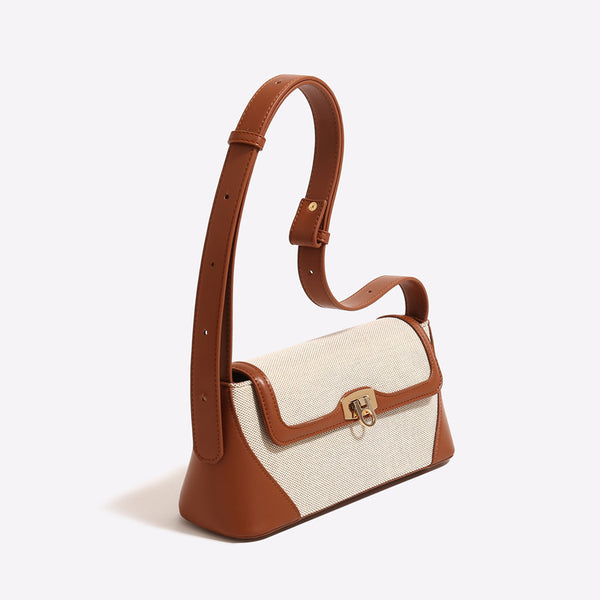 Structured trapezoid flap shoulder bag with canvas-textured body, smooth contrast trim, and gold-tone turn-lock clasp, detail
