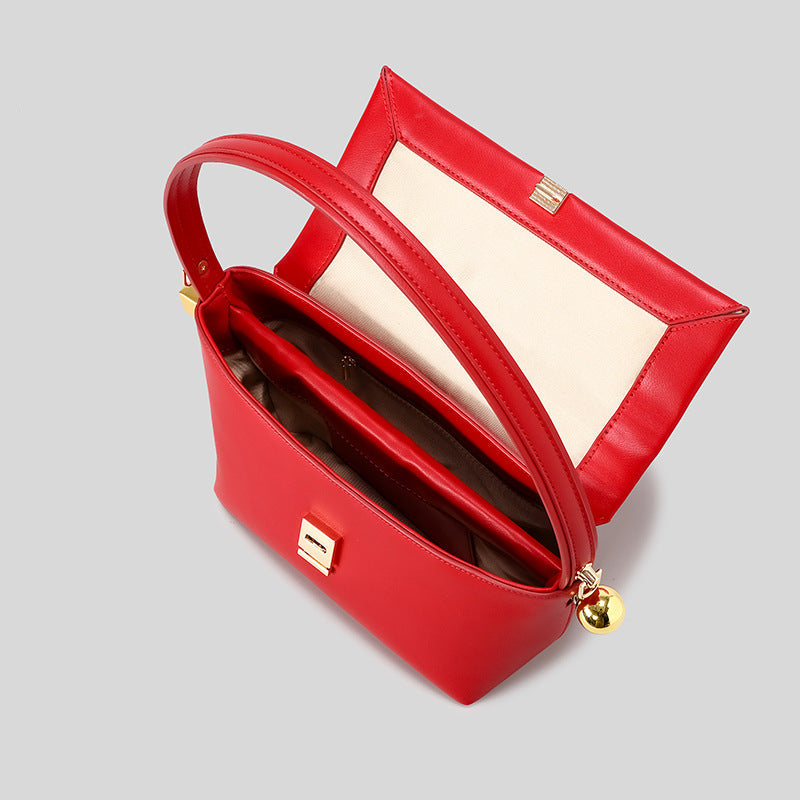 Structured trapezoid flap shoulder bag in red leather-look finish with gold-tone turn-lock clasp, sphere accent, and curved