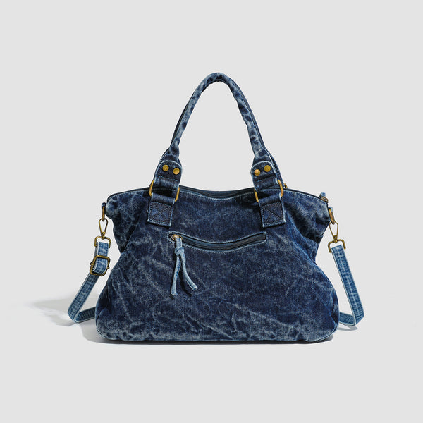 Large washed blue denim-look shoulder bag with gold-tone rings and rivets, top zip closure, front zip pocket, and adjustable