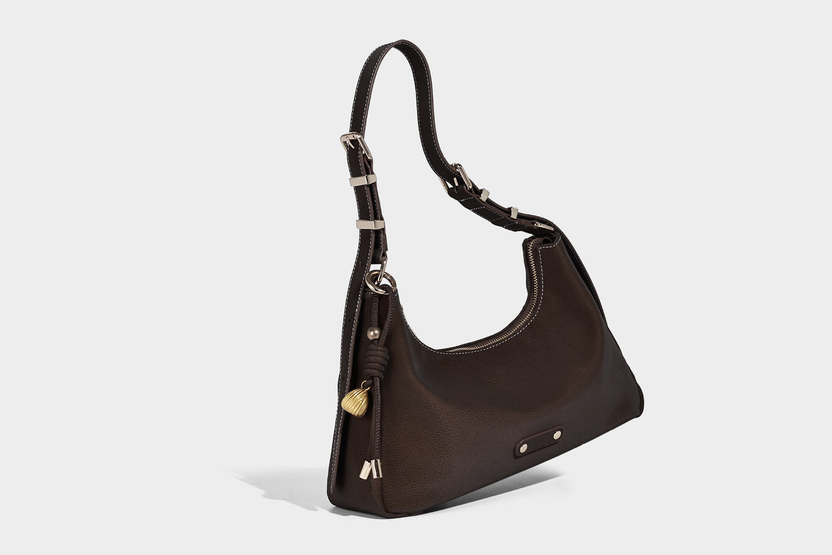 Crescent hobo shoulder bag in pebbled leather-look finish with top zipper, adjustable strap, gold-tone ring hardware, and