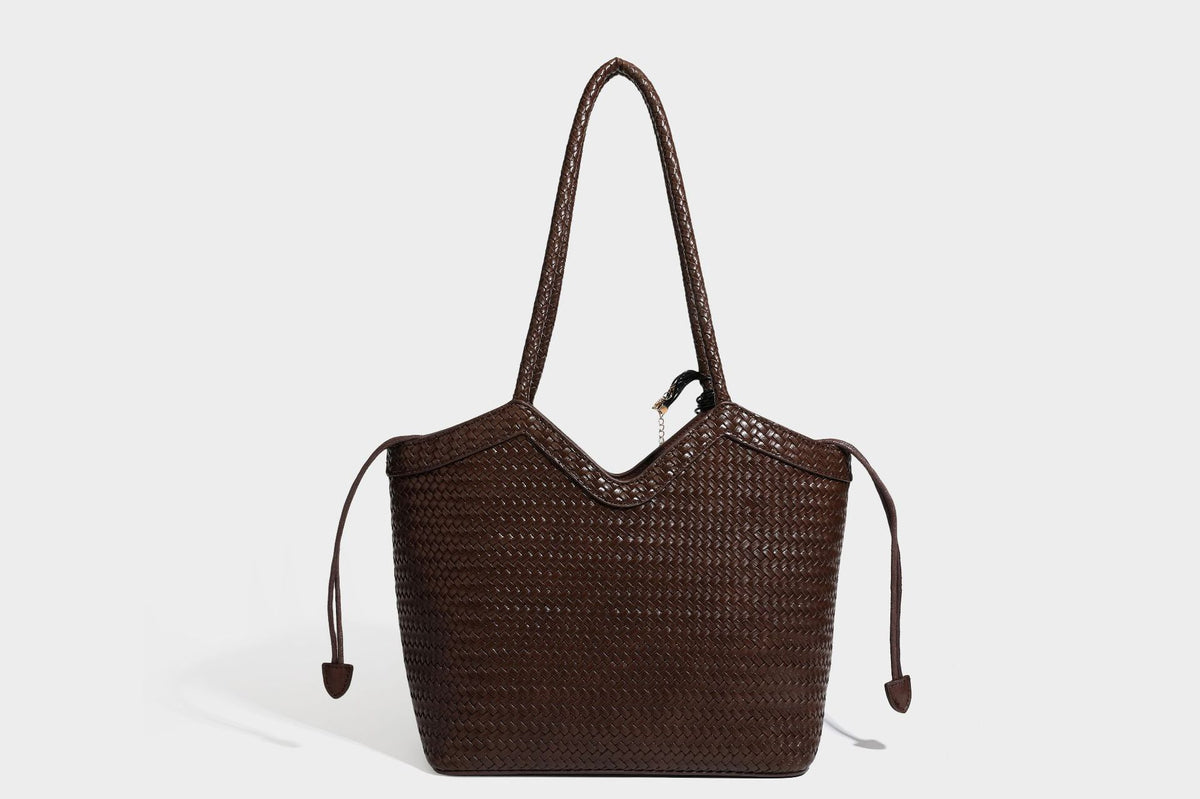 Olivgrüne Tote-Bag in Korbgeflecht-Optik mit dunkelbraunen geflochtenen Schulterriemen, seitlichen Kordelzügen und Perlenanhänger in Goldoptik
