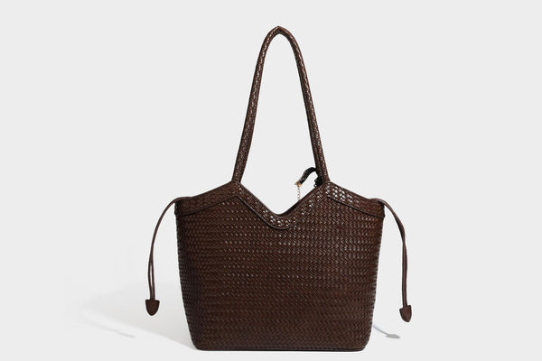Olivgrüne Tote-Bag in Korbgeflecht-Optik mit dunkelbraunen geflochtenen Schulterriemen, seitlichen Kordelzügen und Perlenanhänger in Goldoptik
