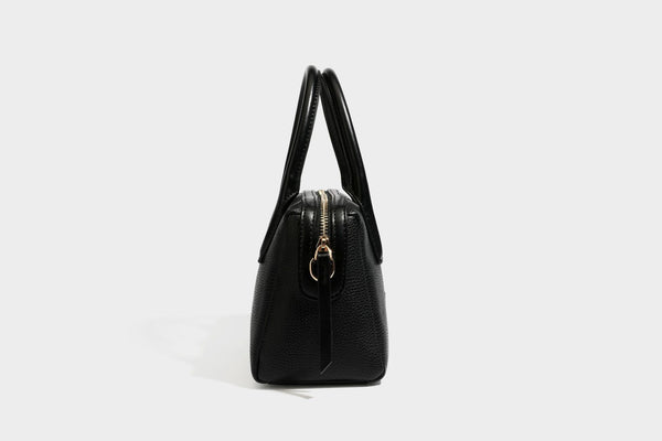 Small structured pillow satchel bag with pebbled leather-look finish, dual rolled top handles, gold-tone gourd emblem, and