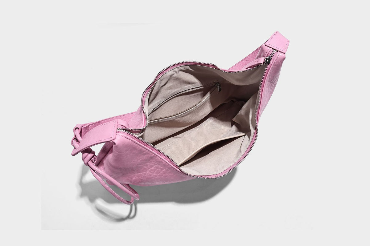 Slouchy crescent half-moon shoulder bag in pink pebbled textured finish with floral charm and knotted side detail, detail