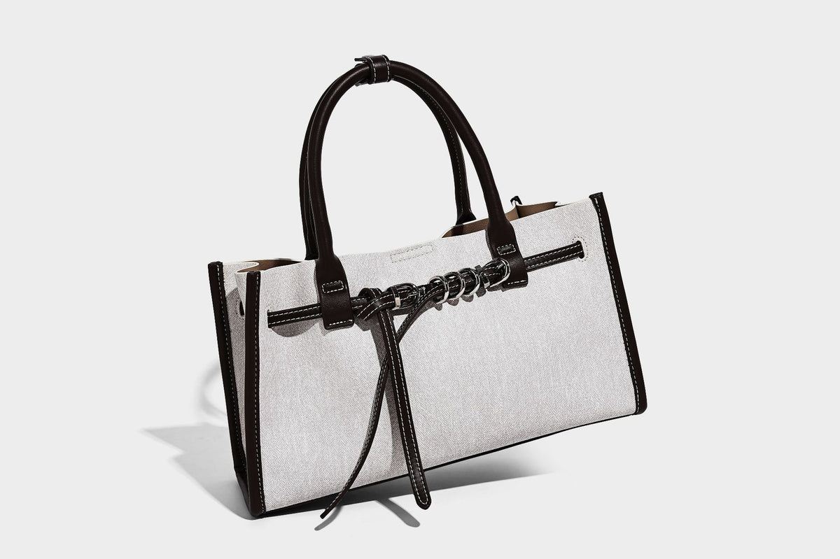 Structured rectangular tote satchel in denim-look fabric with dark trim, knotted front strap hardware, and detachable, detail