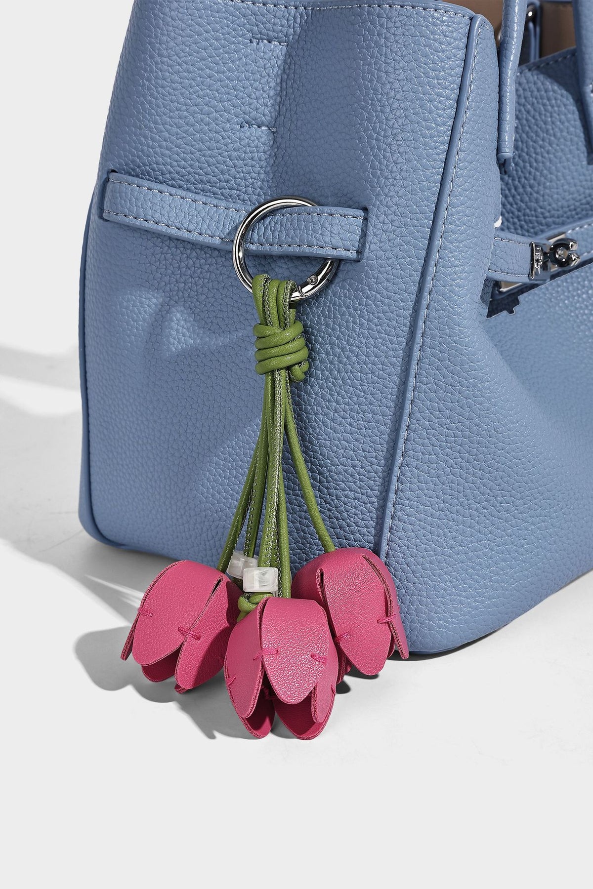 Small structured pebbled bucket tote bag with dual top handles, silver turn-lock front pocket, and detachable shoulder strap