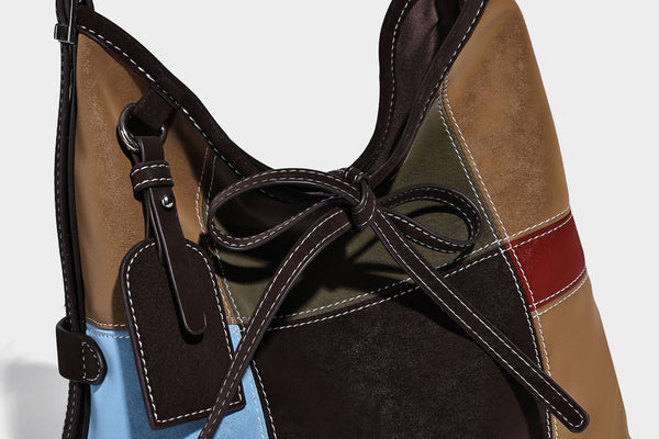 Patchwork bucket tote shoulder bag with tan, dark brown, olive, red, and sky blue color-block panels, white contrast, detail