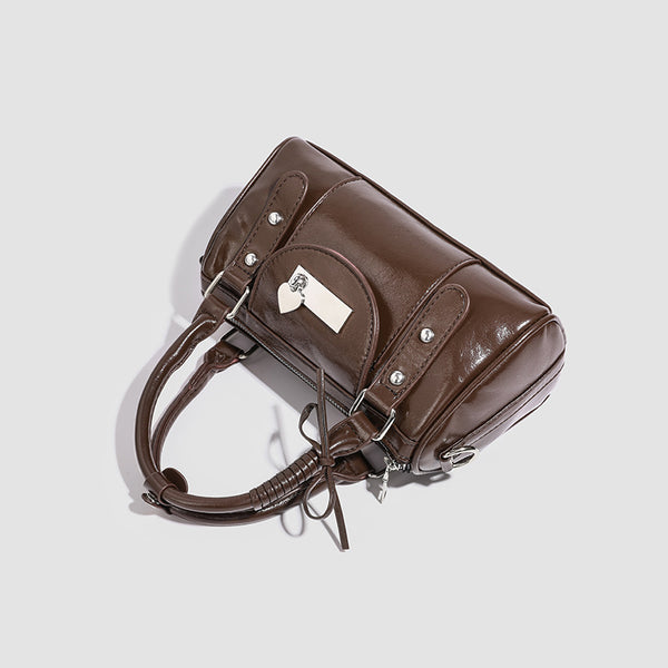 Kleine strukturierte Henkeltasche in glänzender Lederoptik mit Henkeln mit Schleifendetails und Vordertasche mit Herzverschluss, Detailansicht