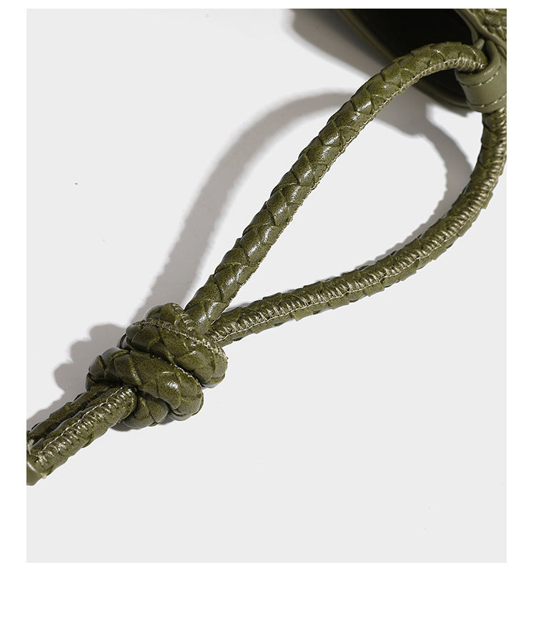 Olive green woven leather-look bucket bag with braided crossbody strap, knotted adjustment, and gold-tone tassel charm with