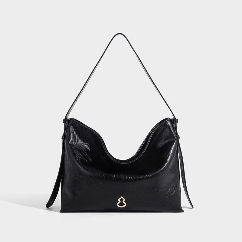 Large slouchy hobo shoulder bag in glossy crinkle leather-look finish with gold-tone emblem hardware and adjustable strap