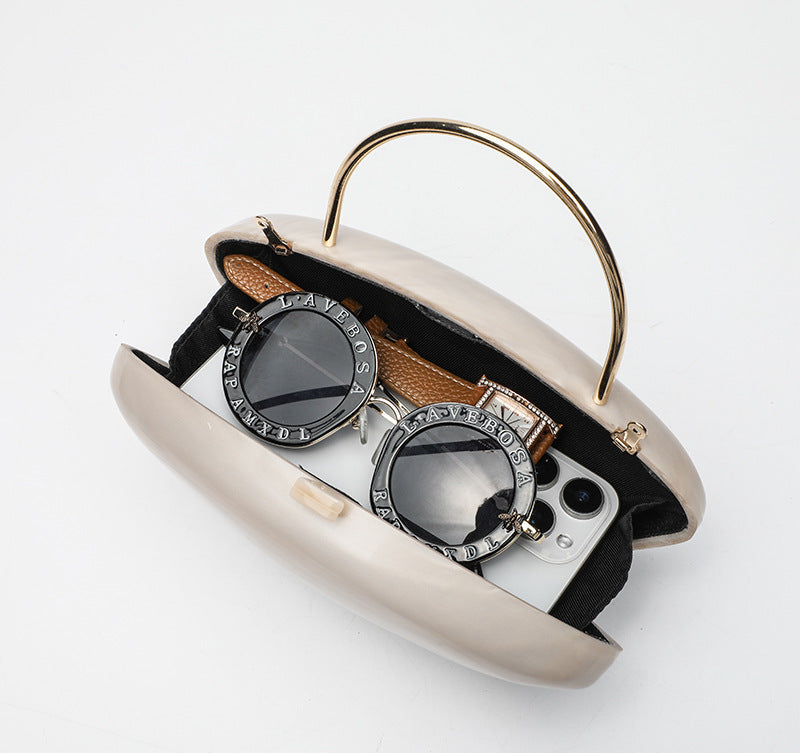 Shell-shaped pearlescent top-handle clutch bag with arched gold-tone metal handle and gold chain strap, detail view 4