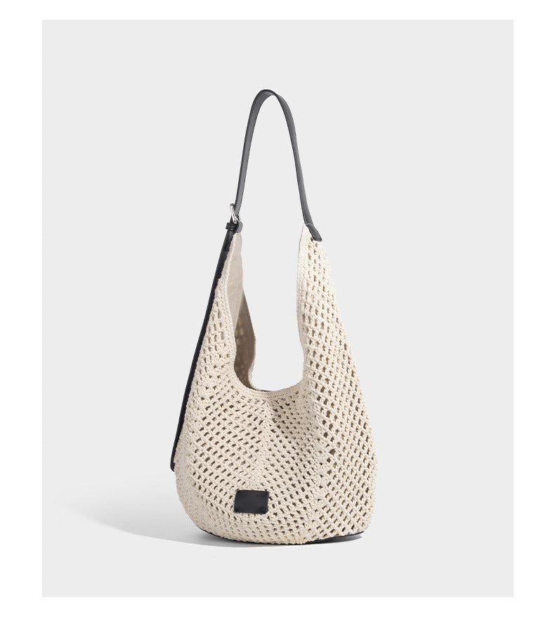 Cream openwork crochet hobo bag with black leather-look strap and trim patch accent, slouchy teardrop silhouette, detail view
