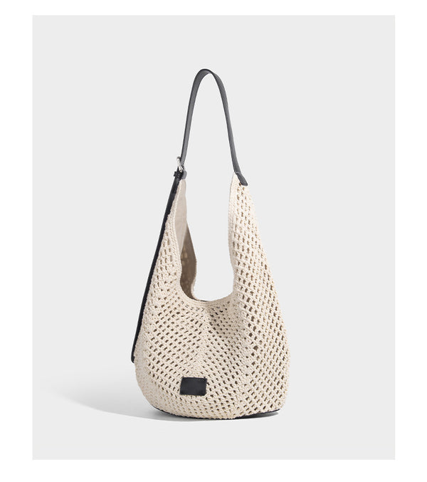 Cream openwork crochet hobo bag with black leather-look strap and trim patch accent, slouchy teardrop silhouette, detail view