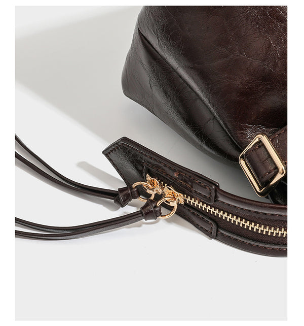 Dark brown glossy crinkled leather-look barrel bag with gold heart lock, dome studs, star charm, dual top handles and, detail