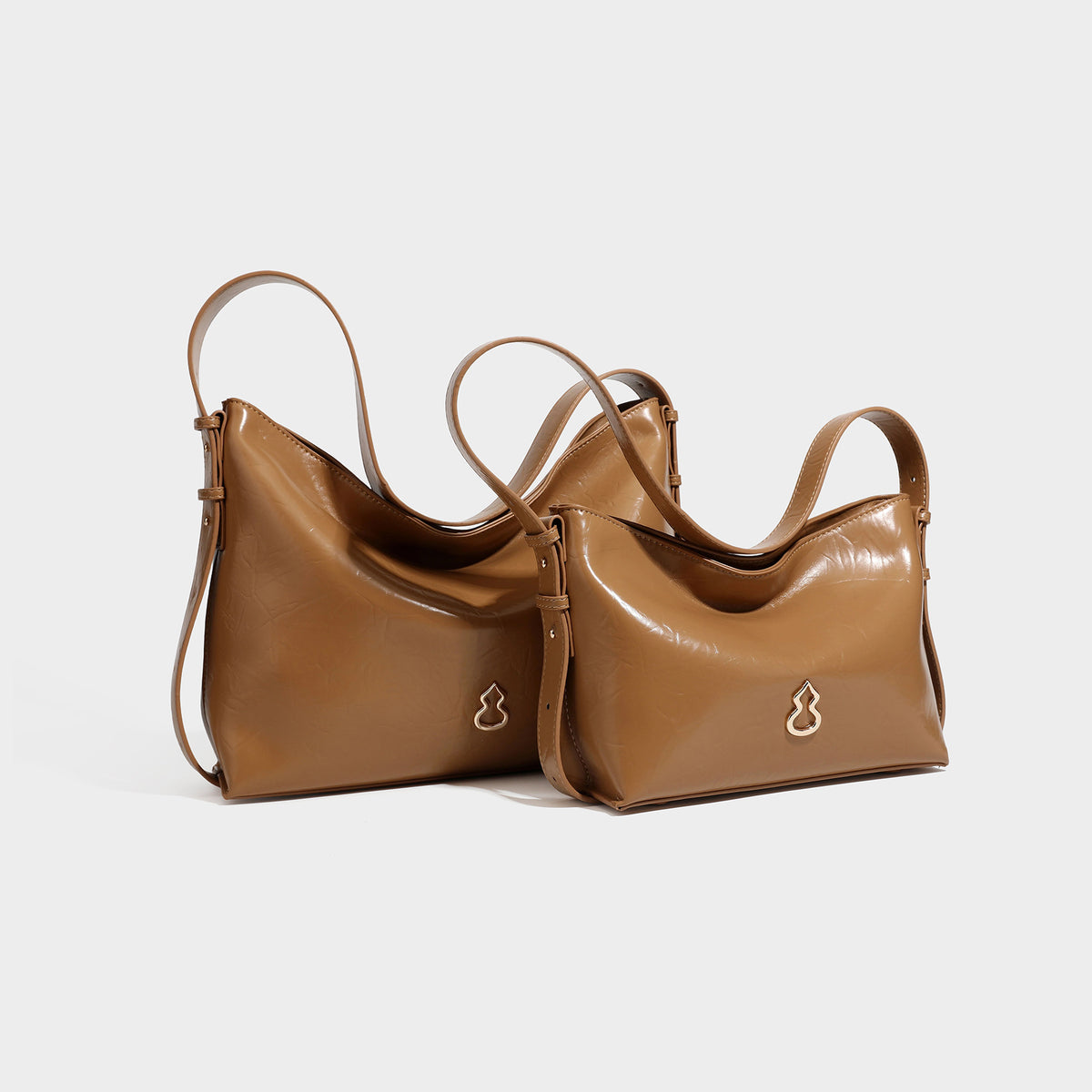 Lässig fallende Hobo-Schultertasche mit offenem Oberteil aus glänzender, karamellbrauner Lederoptik, mit Logo-Beschlägen in Goldoptik und langem, verstellbarem