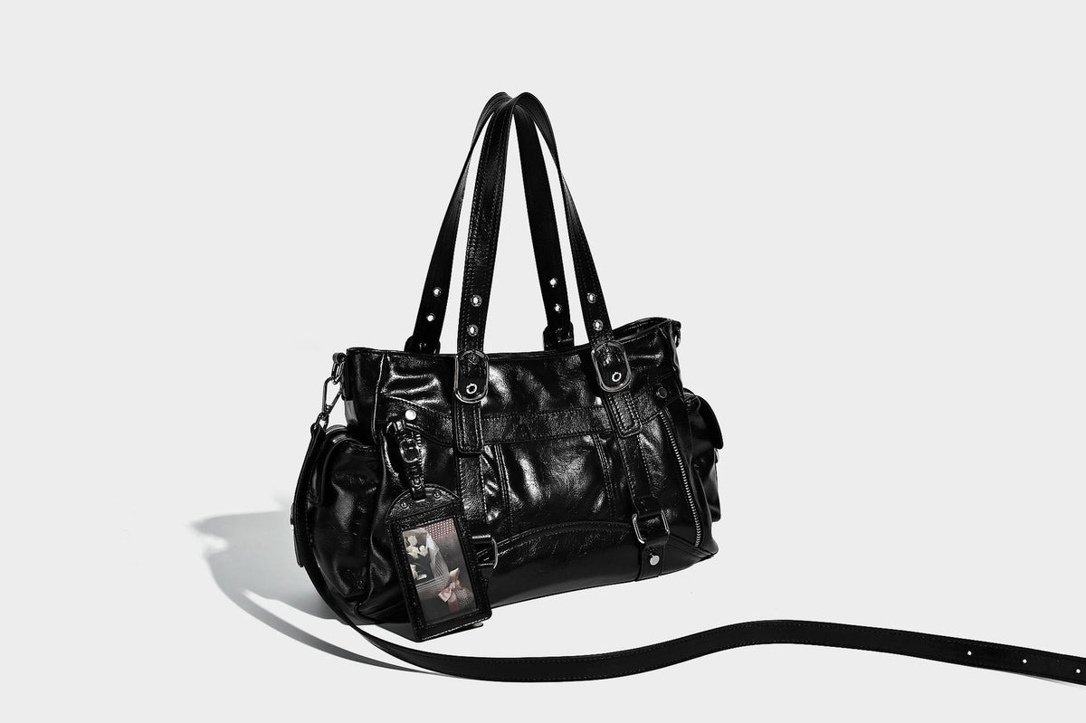 Glossy structured black tote shoulder bag with silver buckle hardware, zip pockets, dual top handles, and detachable, detail