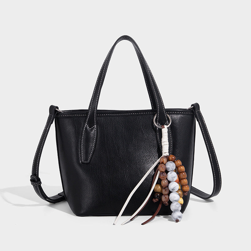 Compact structured bucket tote bag with pebbled textured finish, dual top handles, silver-tone lock hardware, and detachable