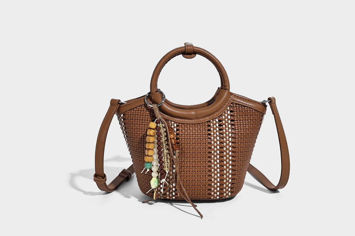 Kleine strukturierte Beuteltasche aus geflochtenem Material mit rundem Tragegriff in Lederoptik, silberfarbenen Beschlägen und perlenbesetztem Quastenanhänger, Detail