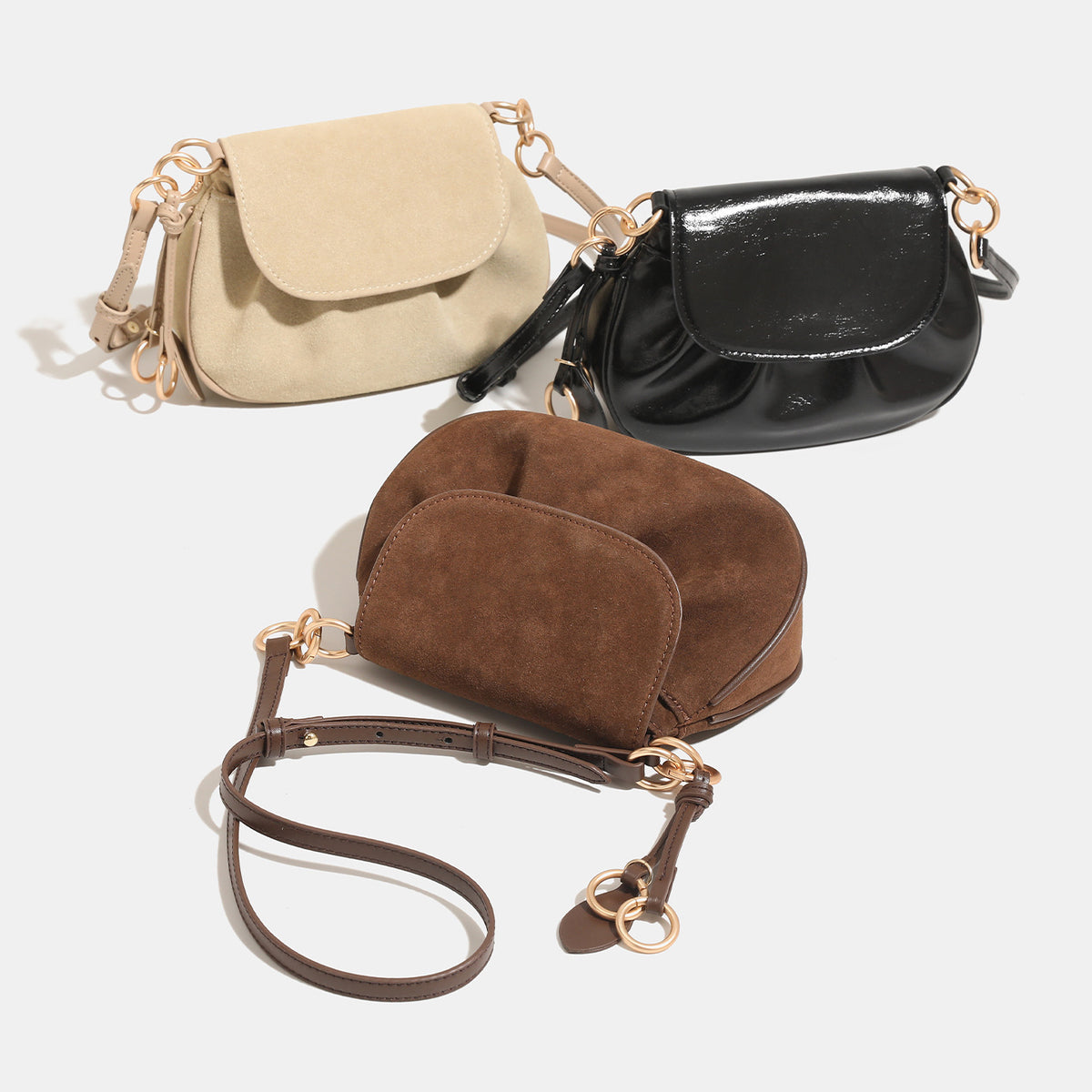 Small rounded flap crossbody saddle bag with gold-tone ring hardware and adjustable strap, detail view 2