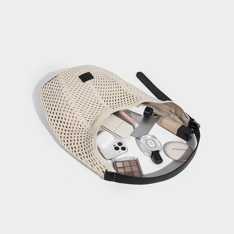 Cream openwork crochet hobo bag with black leather-look strap and trim patch accent, slouchy teardrop silhouette, detail view