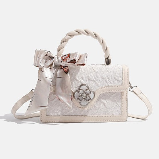 Strukturierte Mini-Crossbody-Tasche in Elfenbein mit geknautschter Oberfläche in Lederoptik, Tragegriff aus einem Seidenschal und silberfarbenem Verschluss in Vierblütenform