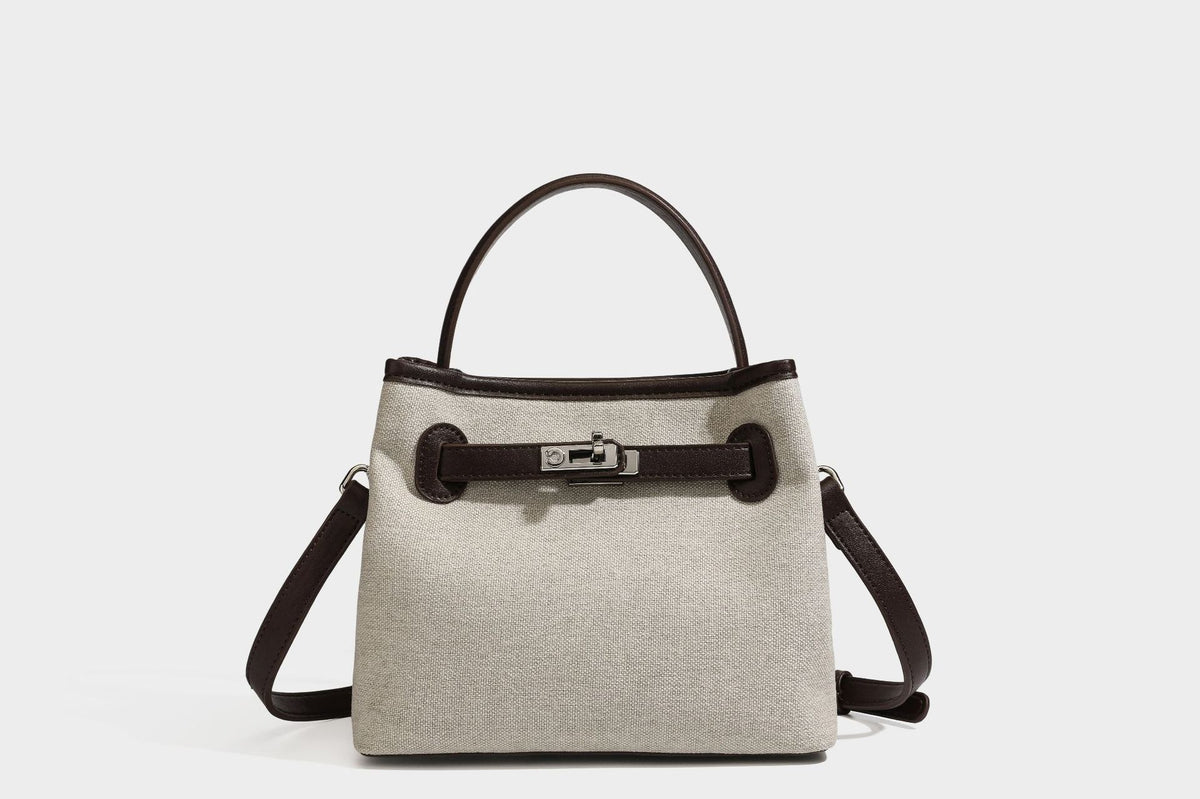 Small structured beige canvas top-handle bag with dark brown leather-look trim, silver turn-lock hardware, and detachable