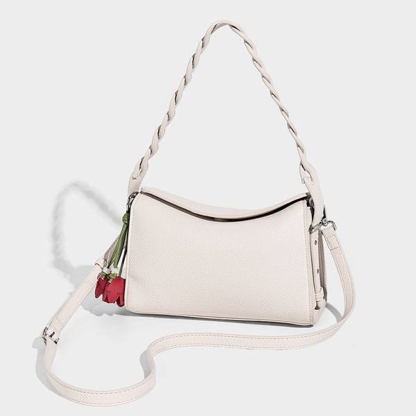 Small structured pebbled-finish shoulder bag with braided top handle, detachable crossbody strap, floral tassel charm, and