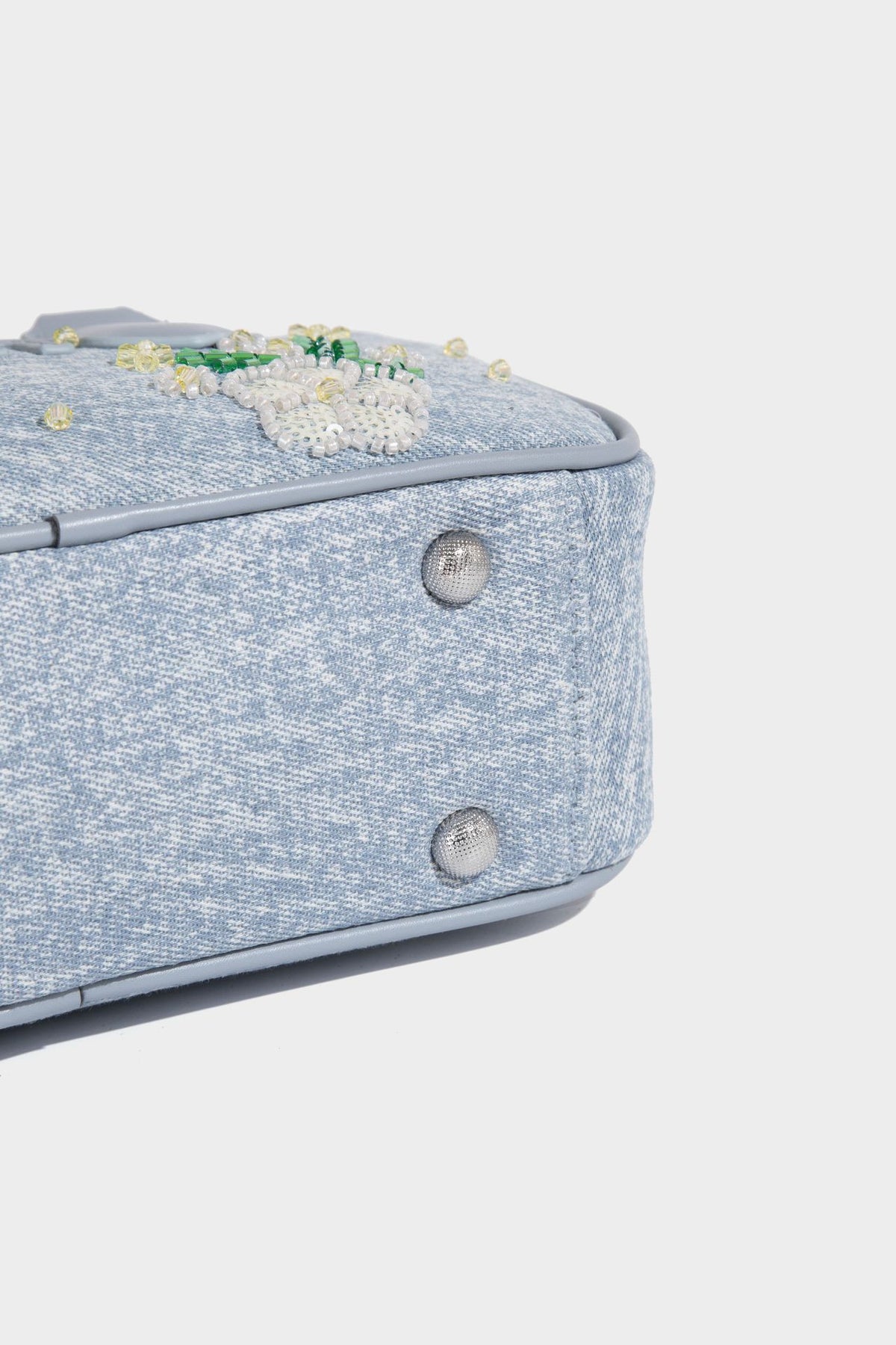Small light blue denim-look barrel bag with white floral bead embroidery, dual top handles, and detachable shoulder strap