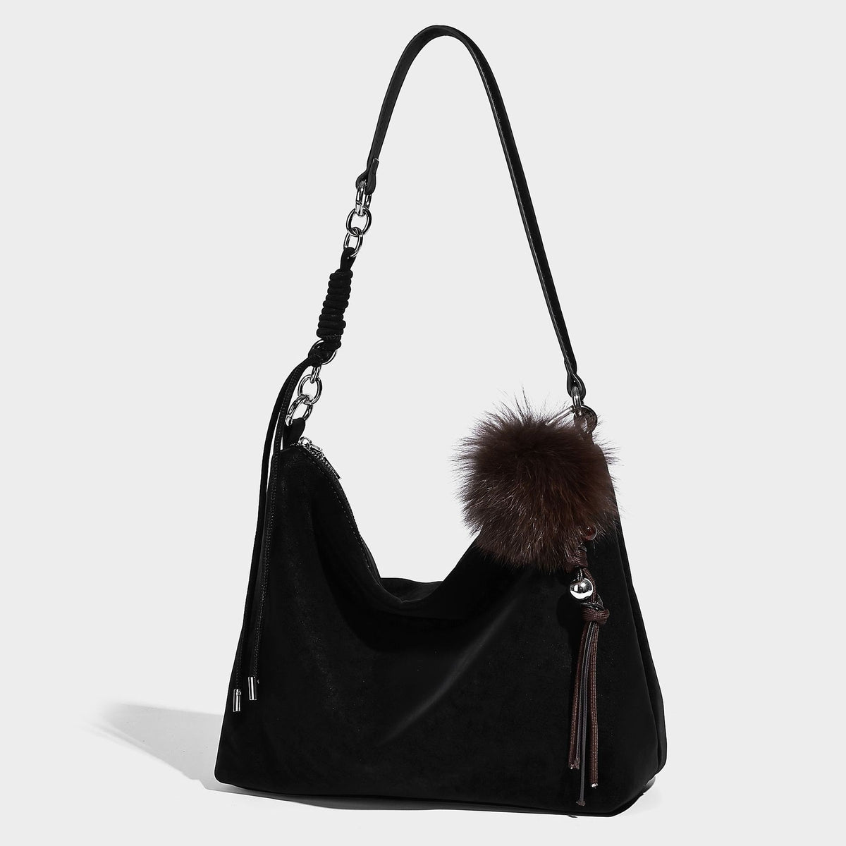 Slouchy matte-finish hobo shoulder bag with tassel cords, silver-tone hardware, and faux-fur pom charm, front view